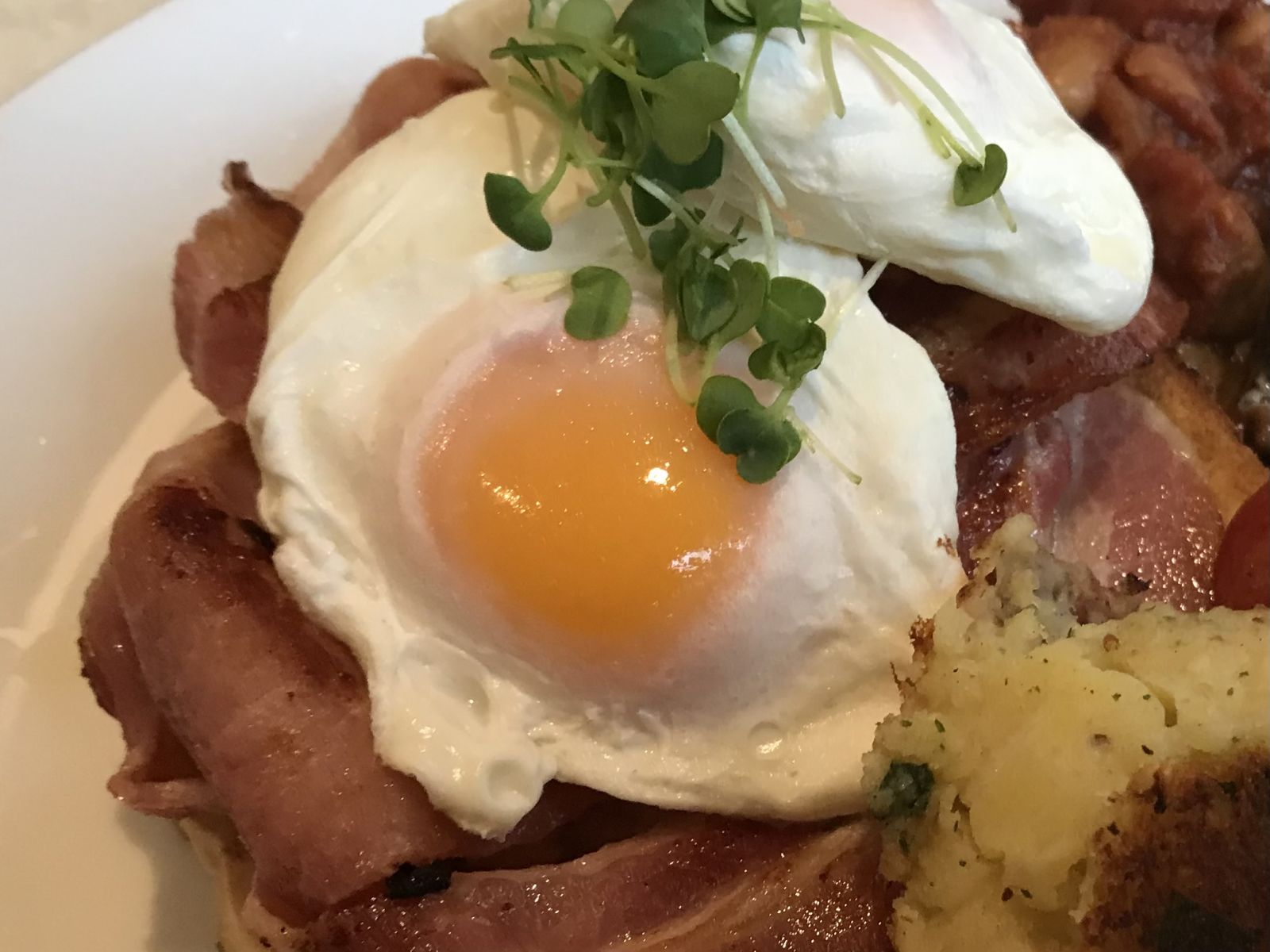 A soft poached egg cooked in the microwave, resting on a spoon over a mug.