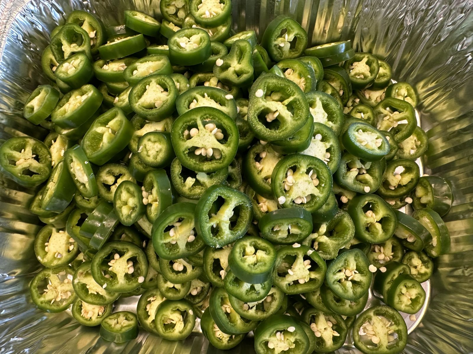 Half-pint jars filled with citrus-honey jalapeño rings in a golden syrup.