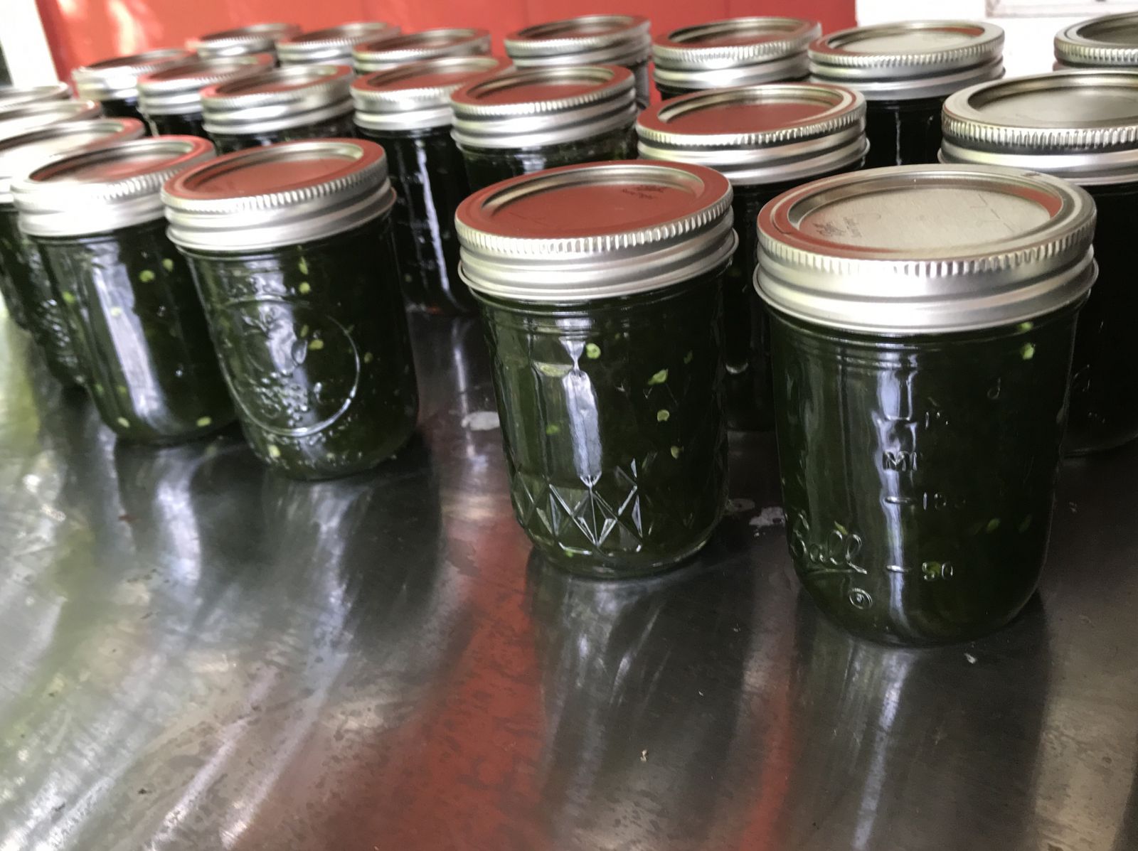 Jars of blueberry jalapeño jam with fresh blueberries and peppers nearby.