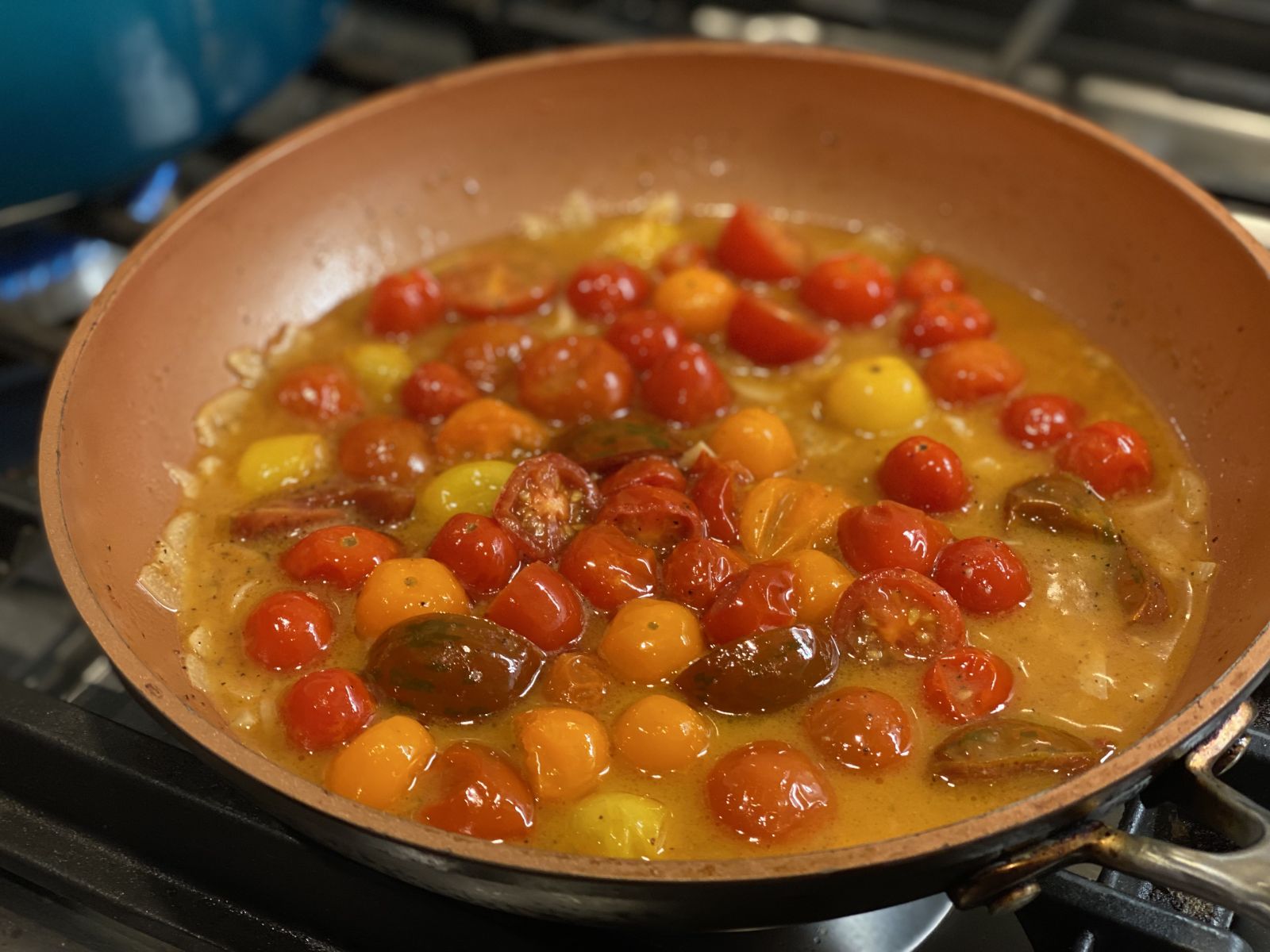 Cherry tomatoes sautéed with garlic, basil, and butter in a skillet.