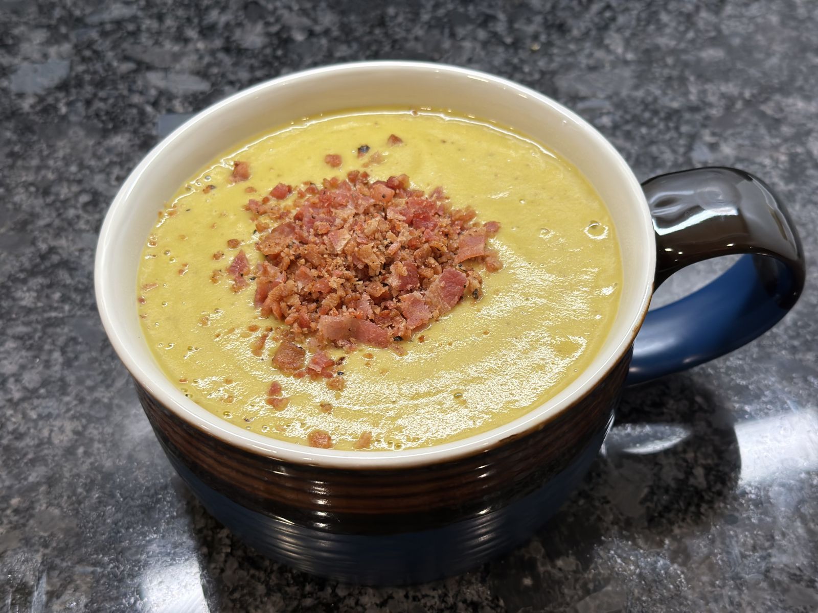 A bowl of creamy broccoli soup topped with cheese and croutons.
