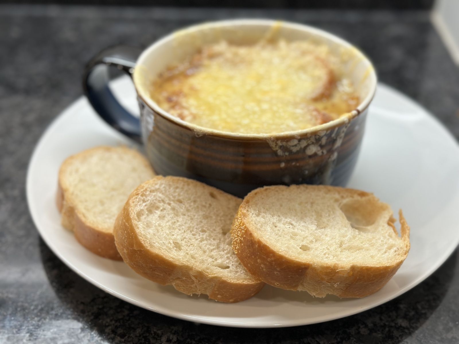 A crock of French onion soup with melted Swiss, Parmesan, and Gruyère cheese.