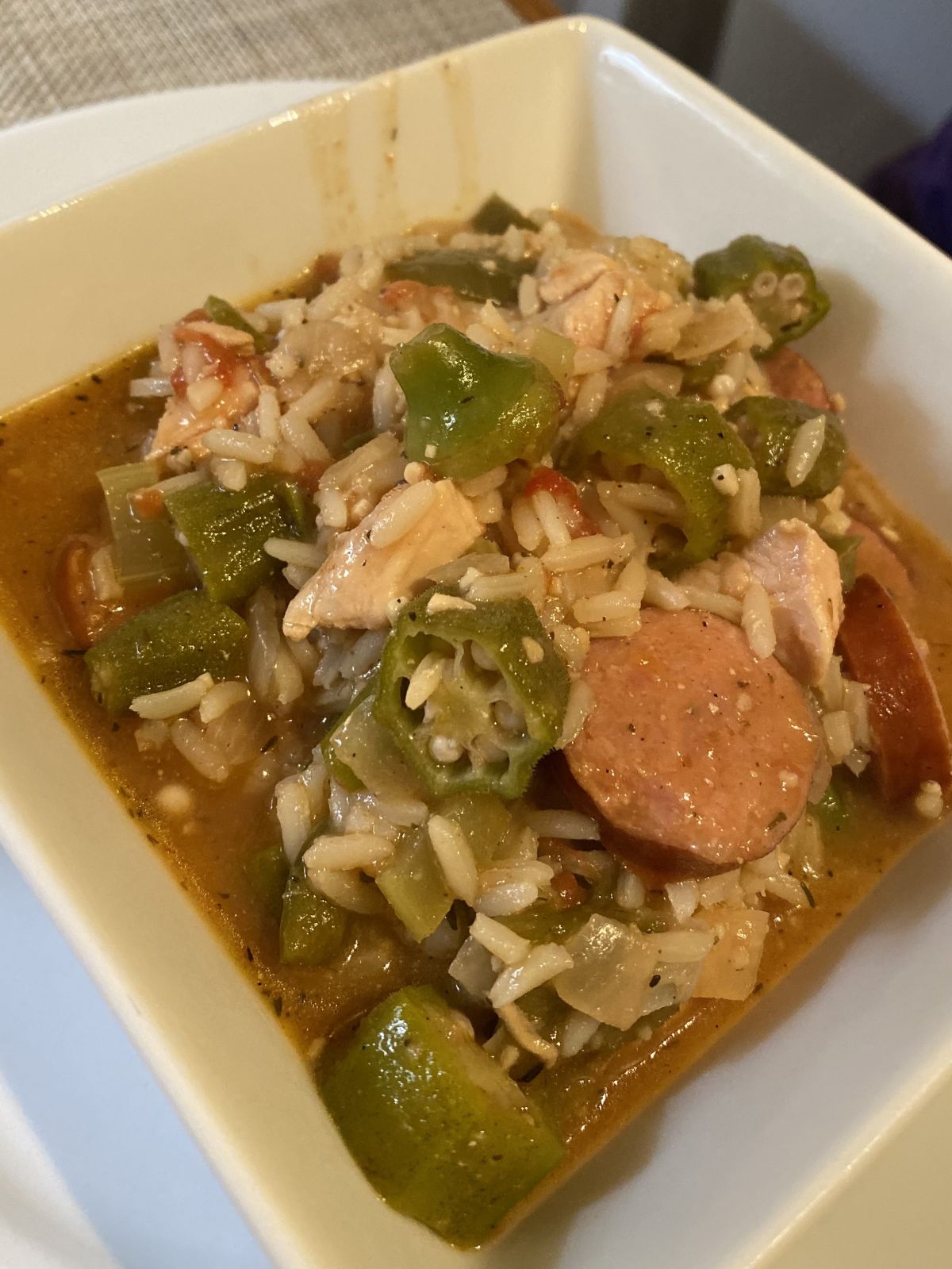 A bowl of gumbo with chicken, sausage, and shrimp served over rice.