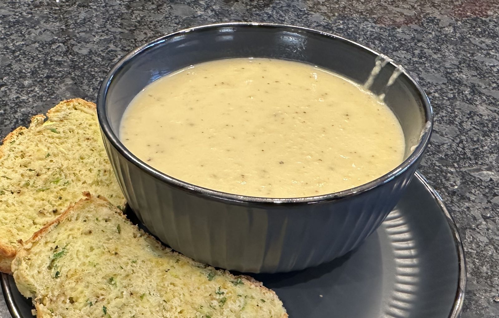 A bowl of creamy Indian-style yellow squash soup garnished with cilantro and coconut milk.