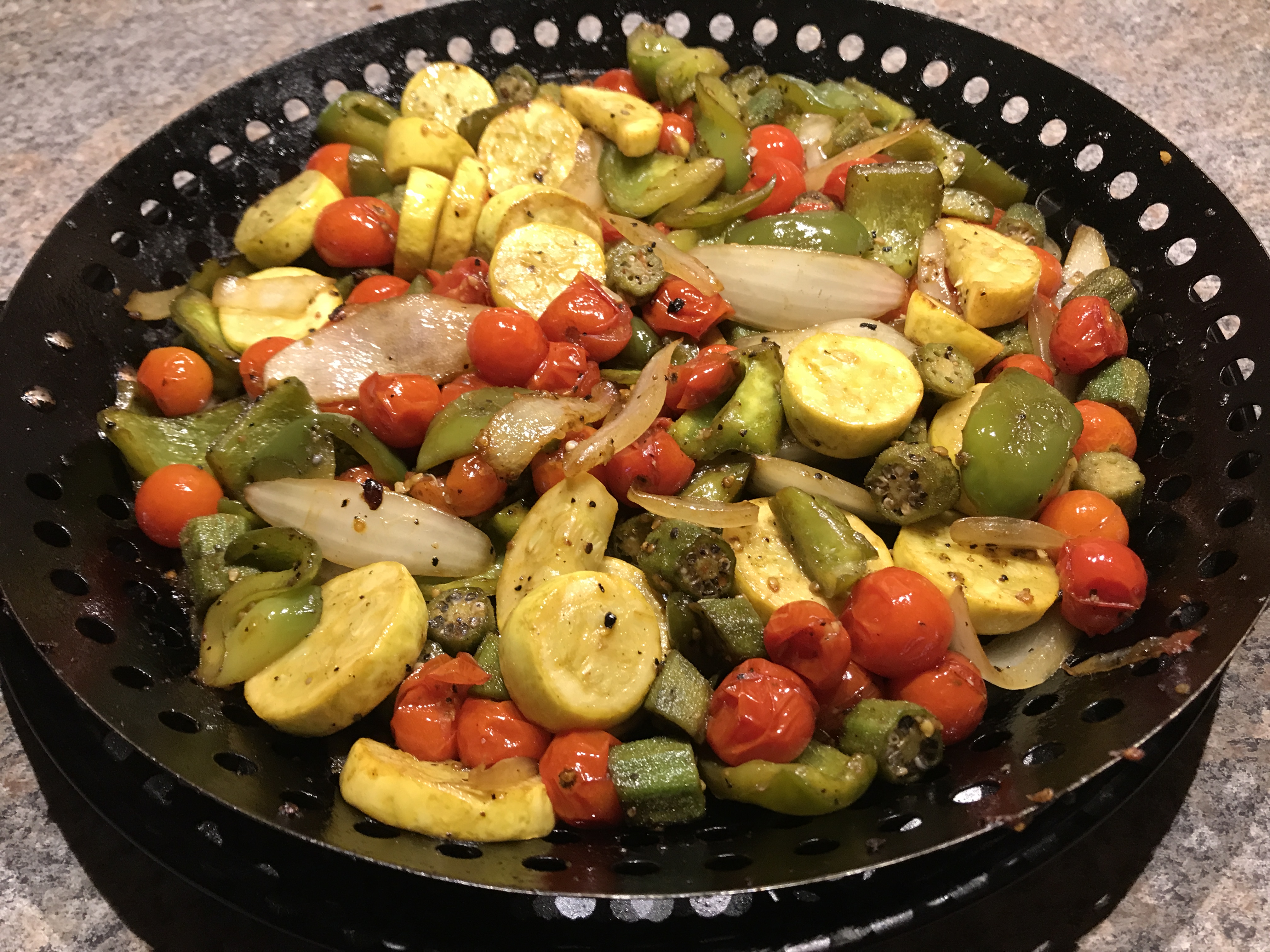 Colorful grilled garden vegetables with yellow squash, zucchini, eggplant, onion, bell pepper, okra, and blistered cherry tomatoes