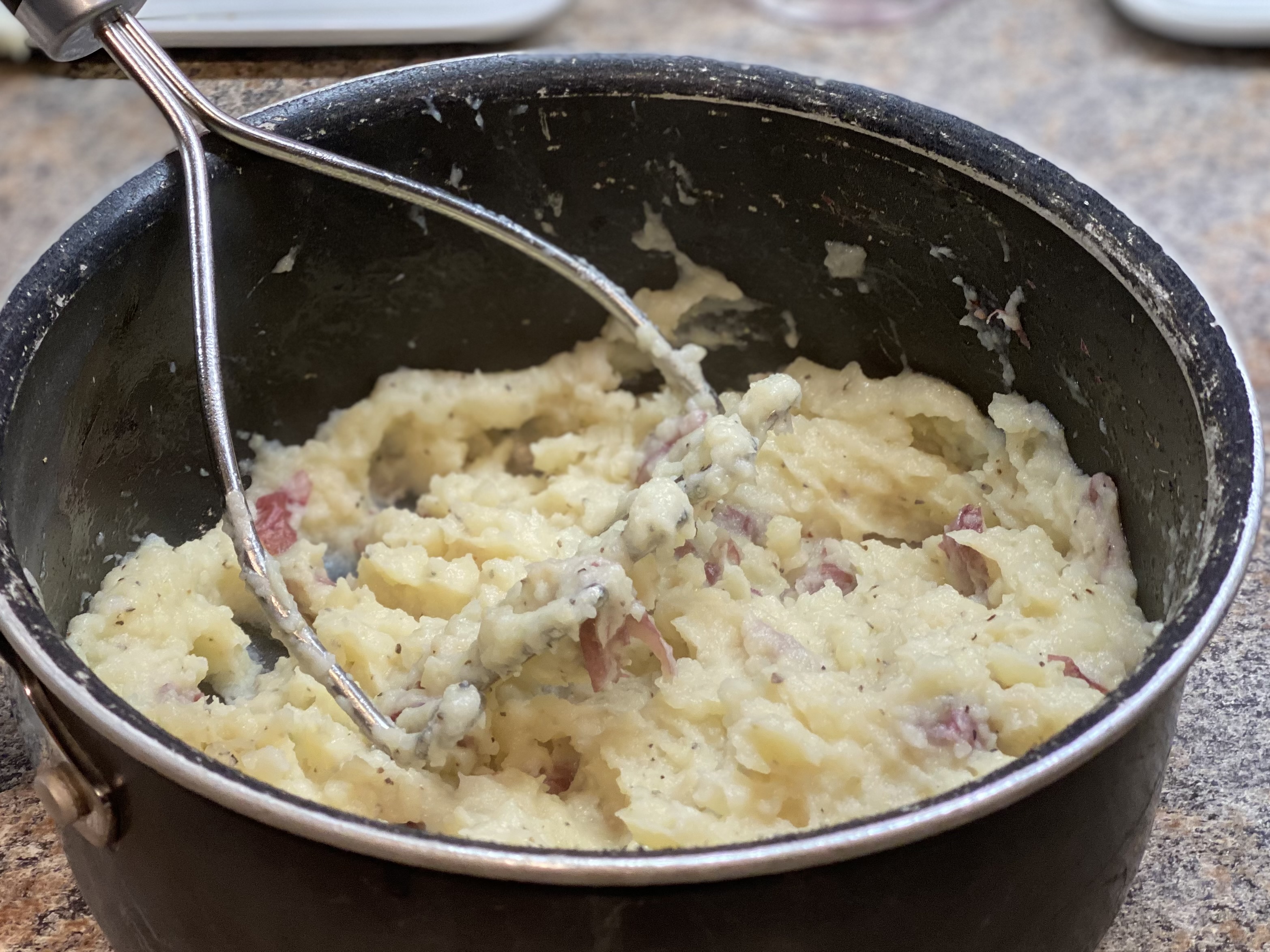 Creamy garlic mashed red potatoes with red skins, butter, black pepper, and fresh herbs